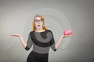 Woman in eyeglasses being confused holding brain