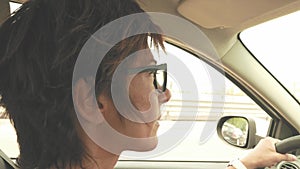 Woman with eyeglasses driving car with hands on steering wheel. Interior close up, side view, traffic on street. Vintage filter, t