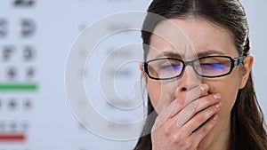 Woman in eyeglasses yawning on ophthalmologic examination, doctor check-up