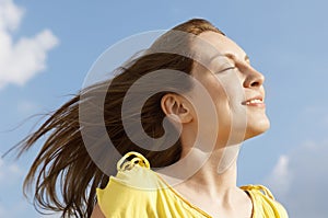 Woman With Eyes Closed Enjoying Sunlight Against Sky