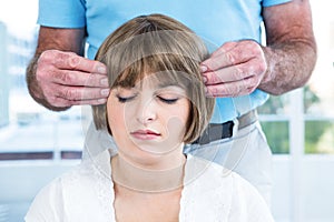 Woman with eyes closed receiving reiki from male therapist