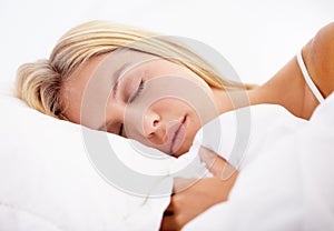 Woman, eyes closed and sleeping on bed in home for good sleep, relaxed or dream in closeup. Girl, hairstyle and face