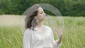 Woman with eyes closed standing in field feeling wind and oneness with nature
