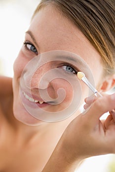 Woman with eyeshadow applicator smiling