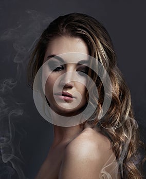 Woman, eyeshadow and makeup, beauty and smoke with hair, cosmetics and balayage on grey background. Serious model, edgy