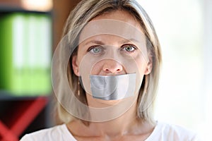 Woman face with adhesive tape covering mouth.