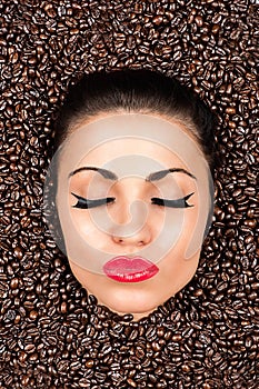 Woman face with closed eyes in the coffee beans