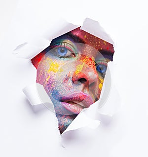 Woman face with colorful makeup in paper hole