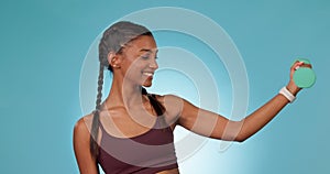 Woman, face and dumbbell in studio, fitness and workout for bicep muscle, pride and power by blue background. Girl