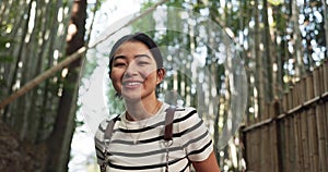 Woman, face and happy in bamboo forest for travel adventure, hiking and relax for journey, nature and park. Portrait