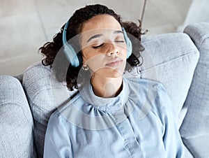 Woman, face and headphones for listening to music for calm, peace and mindfulness on home couch. Young person on living