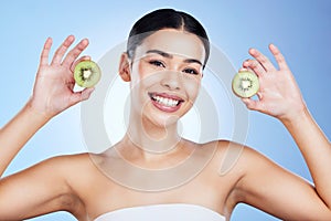 Woman, face and kiwi for skincare nutrition, vitamin C or healthy diet against a blue studio background. Portrait of