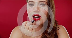 Woman, face and lipstick makeup in studio application for cosmetic beauty, confidence on red background. Female person