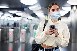 Woman in face mask enter in subway through turnstile