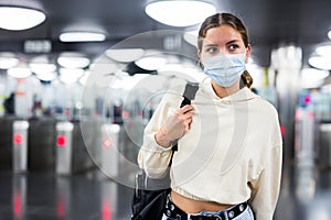 Woman in face mask enter in subway through turnstile