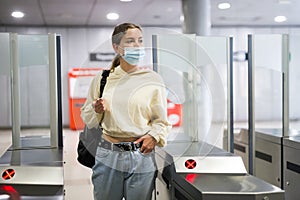 Woman in face mask enter in subway through turnstile