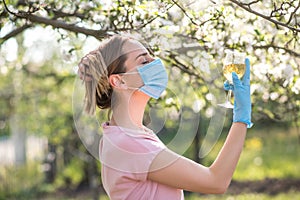 Woman with face mask on quarantine. Stay at home. Family concept. young woman blowing dandelion. glass of champagne on the beach.G photo