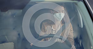 Woman in face mask receiving package with a takeaway food on the go while driving a car