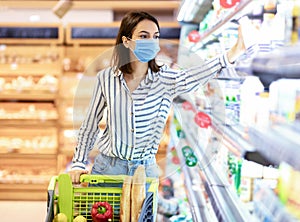 Woman in face mask shopping in supermarket with cart