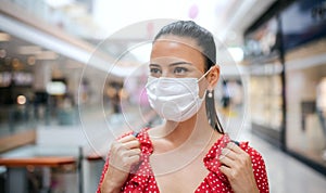 Woman with face mask standing indoors in shopping center, coronavirus concept.