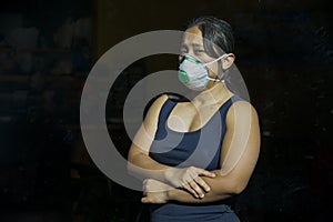 A woman with face mask stands behind glass door