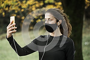Woman with face mask taking video call. Giving lectures while working out during covid-19 photo
