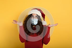Woman with face mask is wondered about something. yellow background