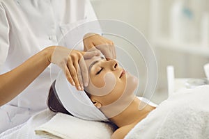 Woman face massage. A professional beautician makes massage treatments for a client in a beauty salon.