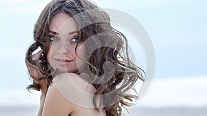 Woman face Portrait on the beach. Happy beautiful curly-haired girl close-up, the wind fluttering hair. Spring portrait on the bea