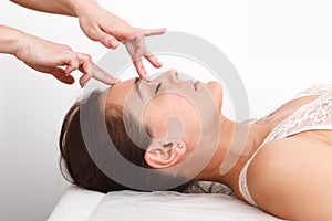 Woman on face skin care procedure, on massage against wrinkles, on white background close-up. Medical center or beauty salon.