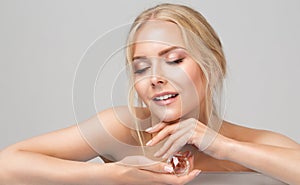 Woman Face Skin Care. Smiling Beauty Model with Closed Eyes holding Crystal under Chin. Women Facial Cosmetics and Cosmetology
