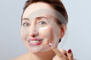 Woman face with Wrinkles and cosmetic cream close up . Collagen and anti aging concept.