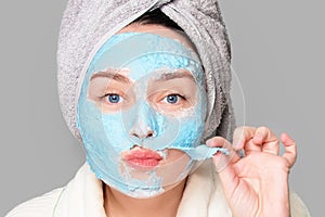Woman with facial clay mask at spa salon or at home, skincare theme. Girl removes alginate cosmetic mask. Face mask, spa
