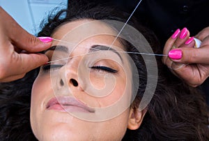 Woman on facial hair removal threading procedure