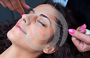 Woman on facial hair removal threading procedure