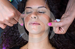 Woman on facial hair removal threading procedure