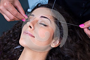 Woman on facial hair removal threading procedure photo