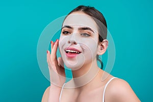 Woman with facial mask over blue studio background. Beautiful young woman with facial white clay mask. Skin care and