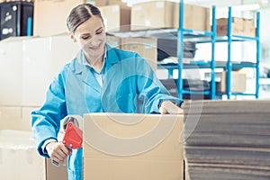 Woman in factory warehouse packaging goods for shipment