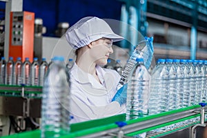 Woman factory worker sterile uniform manufacture drink water. Female specialist factory line for processing and checking bottles
