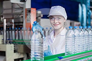 woman factory worker sterile uniform manufacture drink water. Female specialist factory line for processing and checking bottles