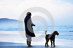 Woman and faithful friend dog alone on stunning beach watching ocean