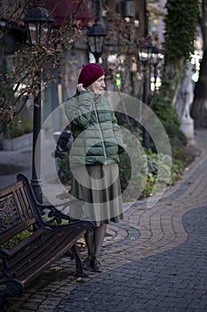 A woman in fall clothes near a bench in the park.