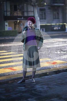 A woman in fall clothing stands in a crosswalk.