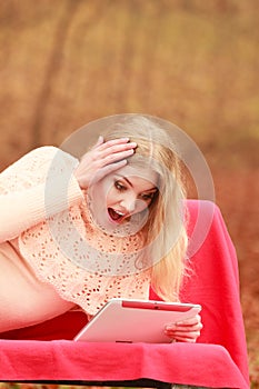 Woman in fall park with tablet browsing internet.