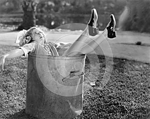 Woman fallen in the garbage bin at the roadside