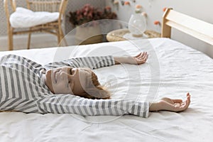 Woman falling down on white bedclothes with arms raised