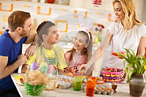 Woman with family preparing Easter basket with eggs