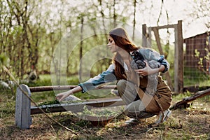 A woman on a farm holding a chicken and smiling a happy smile on an organic farm in the summer sunset