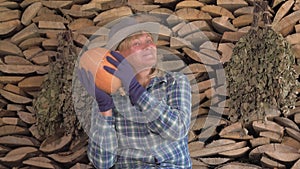 Woman farmer on the background of stacked wood checks the ripeness of pumpkins